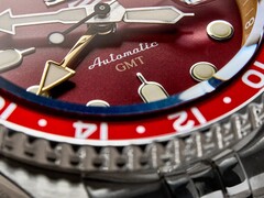 Macro shot of the Seiko 5 Sports GMT HDB016’s burgundy sunray dial, showing its gold-tone GMT hand, luminous hour markers, and rotating bezel