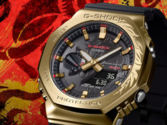 The Casio G-Shock GBM-2100CX-9AJR with an engraved gold bezel, pictured against a stylized red background. (Image source: Casio Japan)