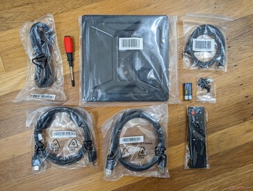 Retail box includes DisplayPort cable, HDMI 2.1 cable, USB-C to USB-C cable, screws, batteries, remote control, screwdriver, and power cord