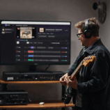 Guitar player plays in front of a monitor showing the app StemKit