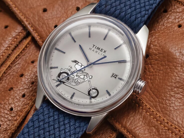 The Peanuts x Timex Marlin Jet Automatic Easy Rider worn on the wrist, showing Snoopy riding a motorcycle on the silver-white dial, blue markers and hands, and a blue woven fabric strap.