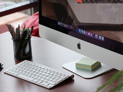 iMac on a desk with the macOS dock visible on screen and an Apple keyboard in front