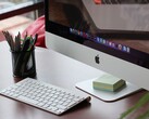 iMac on a desk with the macOS dock visible on screen and an Apple keyboard in front