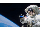 A promotional image for the free NASA+ service featuring an astronaut holding a smartphone with the NASA+ app open in space. (Image Source: NASA)
