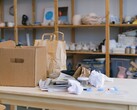 Cardboard box and paper bags on a wooden table in an office with shelves