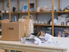 Cardboard box and paper bags on a wooden table in an office with shelves