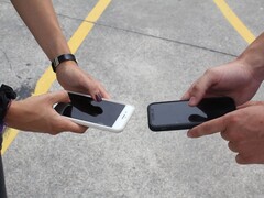 Two people holding two smartphones side by side at a handover