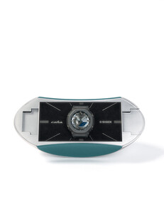 Silver and teal capsule-shaped collector's case for the Casio G-Shock x C2H4 collaboration.