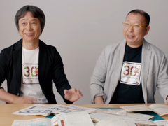 A screengrab of Shigru Miyamoto and Tezuka Takashi wearing Super Mario Bros. 30th anniversary t-shirts