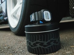 Casio G-Shock DW5600TT25-1 x Toyo Tires watch displayed on a tire-themed metal tin next to a car wheel.