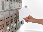 A hand putting an envelope into a row of letterboxes