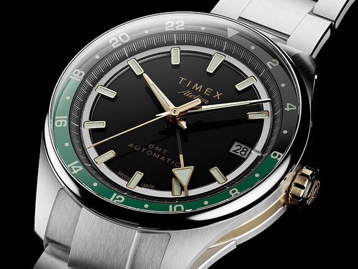 Angled view of the Timex Atelier GMT Première M1a showing its black dial, green GMT ring, gold-tone crown, and stainless steel bracelet.