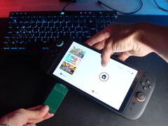 Yu from YouTube channel Better Gaming holding a Nintendo Switch 2 in one hand and an open-source green PCB adapter in the other, attempting to insert it into the device's microSD Express slot (Image source: Better Gaming via YouTube)