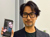 Hideo Kojima showing a poster of Physint on his phone