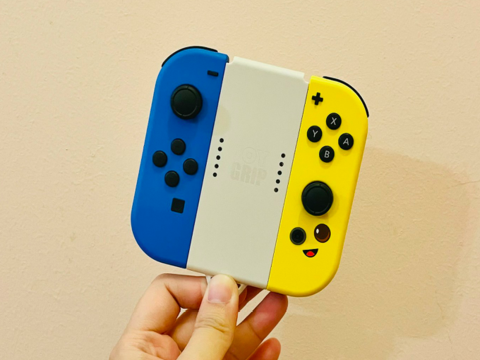 Stock image. A hand holding Joy-Cons (Image source: Gwen King on Unsplash)