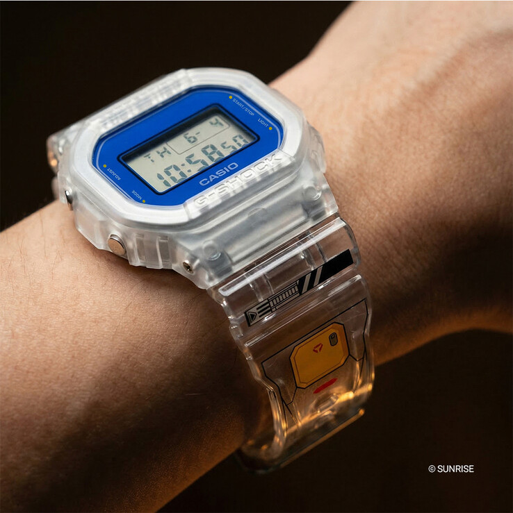 Casio G-Shock x Mobile Suit Gundam DW-5600GM26-7DR worn on the wrist, featuring a transparent resin case and strap, blue bezel surround, and Gundam-inspired graphics on the band.
