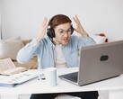 Man wearing headphones raising his hands in frustration in front of a laptop