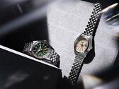 The Seiko 5 Sports Field GMT HDB001 with a green dial and the HDB002 with a cream dial displayed side by side on stainless steel five-link bracelets, each featuring a fixed 24-hour bezel and orange GMT hand.