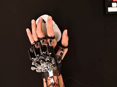 A DIY exoskeleton device strapped to a hand while using a gaming mouse (Image source: Basically Homeless/YouTube)