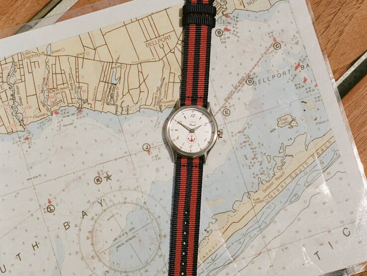 Noah x Timex MK1 Anchor watch with a navy-and-red striped fabric strap resting on a nautical chart.