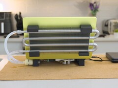 DIY liquid-cooled MacBook Neo setup with external radiator and tubing attached to the laptop