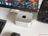 Apple M6 Mac mini on a desk in a gaming setup with a monitor, keyboard, mouse and speaker.