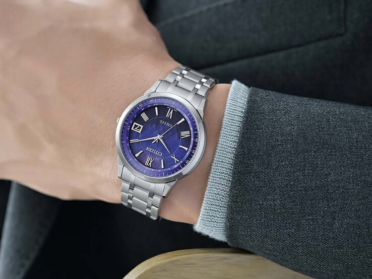 The Citizen Exceed CB1140-79L worn on the wrist, showing its blue dial, silver-tone case, and integrated titanium bracelet against a dark jacket.