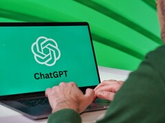 A man is typing on a laptop with the ChatGPT logo visible on the screen