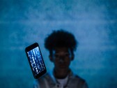 Floating smartphone with code on its screen in front of a blue background, with a blurred person behind it