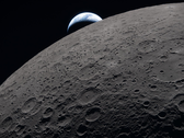The lunar surface fills the frame in sharp detail, as seen during the Artemis II lunar flyby, while a distant Earth sets in the background.