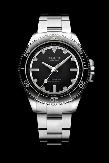 The dial is black enamel with gold hands and markers, ringed by a diamond-cut black and green 24-hour track.