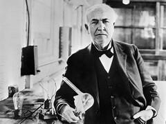 Thomas Edison with the light bulb he invented in 1883 (Unknown photographer, Public domain, via Wikimedia Commons)