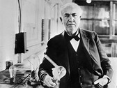 Thomas Edison with the light bulb he invented in 1883 (Unknown photographer, Public domain, via Wikimedia Commons)
