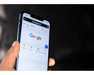 A photo of a hand holding a smartphone with the Google Search homepage open on screen. (Image Source: Solen Feyissa on Flickr)
