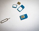 SIM cards in three sizes and an ejector pin on a white surface