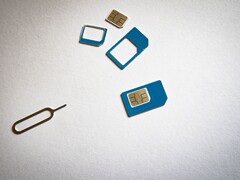 SIM cards in three sizes and an ejector pin on a white surface