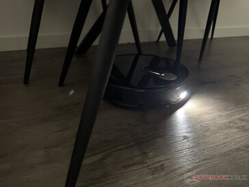 The Roborock Qrevo Slim with its light switched on in the chair leg maze