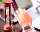 Hourglass next to a hand on a laptop keyboard