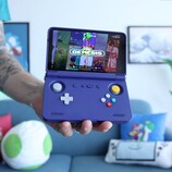 Retro Game Corps’ Russ holding the Retroid Pocket Flip 2 handheld gaming console in purple, with the screen displaying a Sega Genesis emulator interface. (Image source: Retro Game Corps on YouTube)