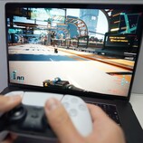 Osoba grająca w Cyberpunk 2077 na MacBooku przy użyciu kontrolera DualSense, prezentująca natywną wydajność gier na macOS. (Źródło obrazu: Andrew Tsai / YouTube)