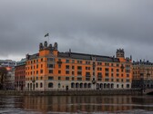 Orange Rosenbad building with a Swedish flag by the water in Stockholm under a cloudy sky