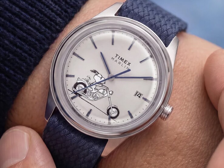 The Peanuts x Timex Marlin Jet Automatic Easy Rider worn on the wrist, showing Snoopy riding a motorcycle on the silver-white dial, blue markers and hands, and a blue woven fabric strap.