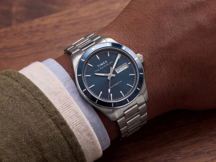 Timex Waterbury Heritage Automatic with blue enamel dial worn on a wrist, showing its silver-tone case and stainless-steel bracelet.