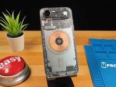 Transparent iPhone Air showing internal components and copper charging coil on a wooden desk. (Image source: Phone Repair Guru via YouTube)