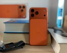 Apple iPhone 17 Air in orange finish showing rear design and camera module placed on stacked books