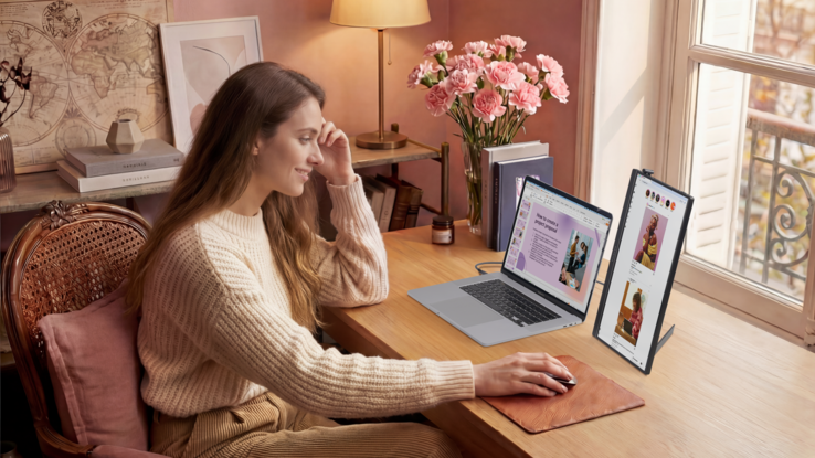Woman working at desk on portable monitor and laptop