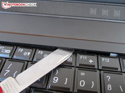 The keyboard's screws can be accessed using a thin object.