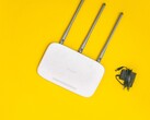 White Wi-Fi router with three antennas and a power supply on a yellow background