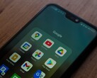 Smartphone on a wooden desk with an open Google app folder