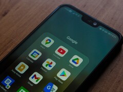 Smartphone on a wooden desk with an open Google app folder